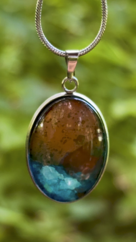 Torchbearer Twelve Specimen One wearable copper specimen pendant featuring vivid verdigris blue formations beneath a weathered copper-gold landscape, preserved between glass and stainless steel.