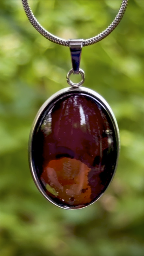 Torchbearer Twelve Specimen Two wearable copper specimen pendant displaying deep mahogany red, bronze and copper tones reminiscent of a shadowed geological cross-section, preserved between glass and stainless steel.