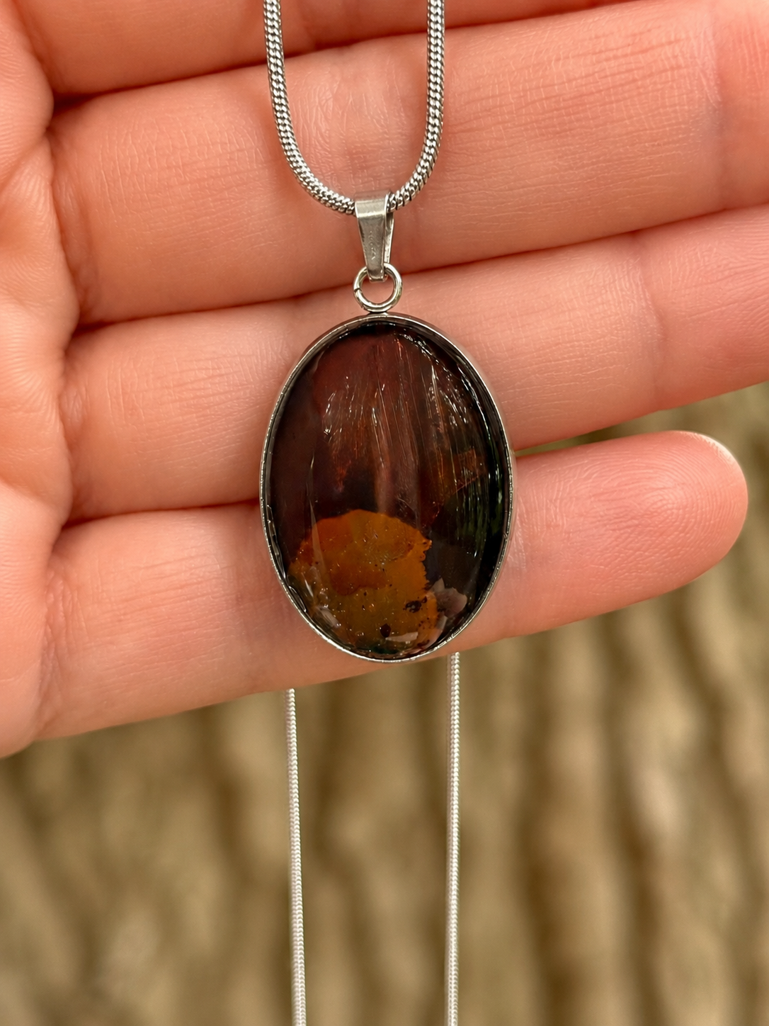 Torchbearer Twelve Specimen Two wearable copper specimen pendant displaying deep mahogany red, bronze and copper tones reminiscent of a shadowed geological cross-section, preserved between glass and stainless steel.